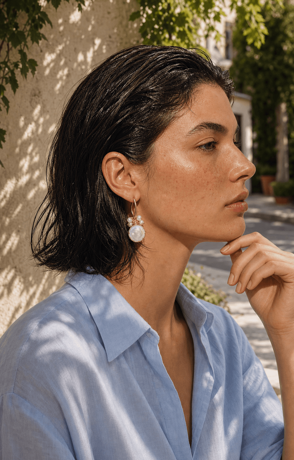 Model in pale linen wearing pearl jewelry outdoors